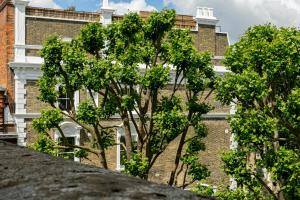 a brick building with trees in front of it at PenthouseStays Notting Hill - Chic 2 Bedroom Apartment w/ King Beds - near Portobello Road & Kensington High Street in London
