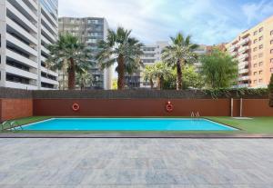 a swimming pool with palm trees and buildings at Stay U-nique Apartments Venecuela in Barcelona