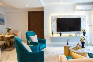 salon z niebieskimi krzesłami i telewizorem z płaskim ekranem w obiekcie Blue Bee 2 Bedroom Apartment w mieście Lagos