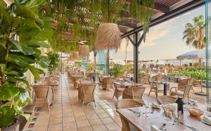 un restaurant avec des tables, des chaises et des plantes dans l'établissement Hotel Porto Santa Maria - PortoBay - Adults Only, à Funchal