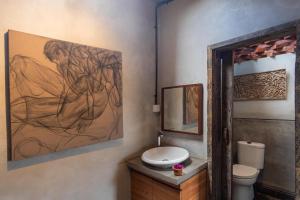bagno con servizi igienici e un dipinto sul muro di Rumah Paros & Gallery a Sukawati