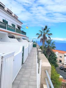 una passerella accanto a un edificio bianco vicino all'oceano di Sunny Holidays in Casa Familiar Playa La Arena a Puerto de Santiago