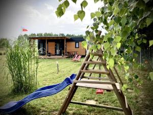 een houten ladder naast een boom met een huis bij Cisy Resort-idealny dla gości ze zwierzętami,ogrodzony teren na wyłączność,150 m od jeziora in Ełk