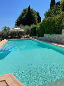 a large blue swimming pool with an umbrella at Casa le Querce in Castiglione del Lago