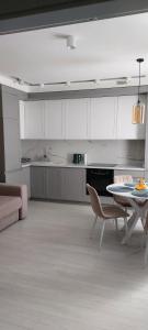 een keuken met witte kasten en een tafel en stoelen bij Новые апартаменты Lux in Chişinău