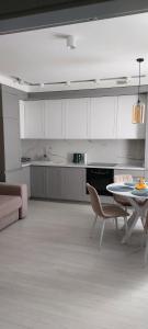 - une cuisine avec des placards blancs, une table et des chaises dans l'établissement Новые апартаменты Lux, à Chişinău