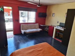 Cette chambre dispose d'une chaise, d'un bureau et de murs rouges. dans l'établissement Independent Apartment Wifi A C, Stove, Refrigerator, Tv, à Mérida
