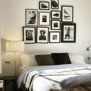 a bedroom with a large bed with framed pictures on the wall at Pescallo Apartments in Bellagio