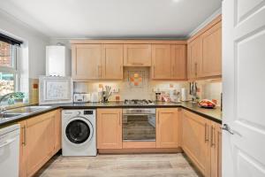 a kitchen with wooden cabinets and a washer and dryer at PRIME 3 BED HOUSE to BICESTER OUTLET for 8 People by Platinum Key Properties in Bicester