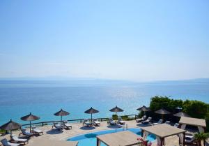 a pool with chairs and umbrellas next to the ocean at Blue Bay Halkidiki in Afitos