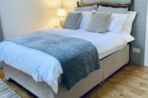 a large bed with a blue comforter and pillows at Wavecrest Holiday Cottage in Garryvoe