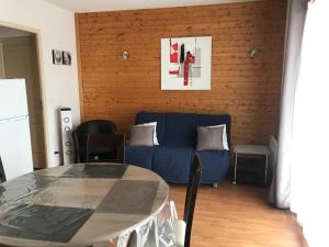 un soggiorno con un divano blu e un tavolo di Bel appartement en résidence avec piscine a Orelle