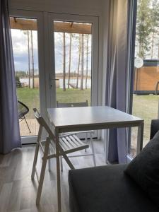 una mesa y una silla en la sala de estar en Makosieje Resort - komfortowy domek 30m od jeziora,ogrzewanie,wi-fi,widok na jezioro en Makosieje