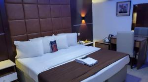 a hotel room with a bed with a book on it at Presken Hotel and Resorts MOJIDI in Ikeja
