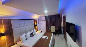a bedroom with a large bed and a television at Presken Hotel and Resorts MOJIDI in Ikeja