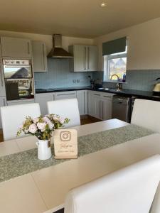 a kitchen with a table with a vase of flowers on it at Lake View Lodge in Saint Columb Major