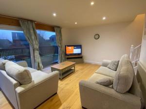 a living room with two couches and a tv at Lake View Lodge in Saint Columb Major