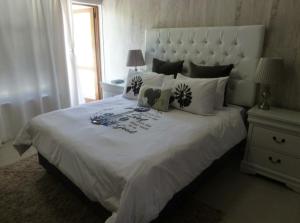 - une chambre avec un grand lit blanc et des oreillers dans l'établissement Springbok Apartments, à Springbok