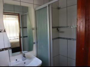 a bathroom with a shower and a sink and a mirror at Springbok Apartments in Springbok