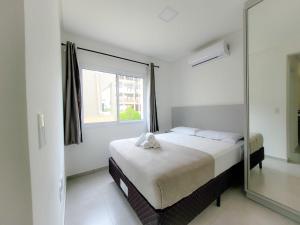 a bedroom with a bed and a large window at Hospeda Mariscal Flat in Bombinhas
