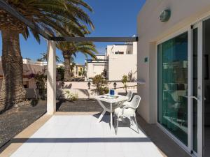 une terrasse avec une table, des chaises et un palmier dans l'établissement HomeForGuest Apartamento Alisios 1 con piscina en Corralejo, à Corralejo
