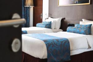 two beds in a hotel room with blue and white at Best Western Elyon Colombo in Colombo