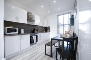 uma cozinha com armários brancos e uma mesa preta em Beautiful Apartment by Town & Beach em Swansea