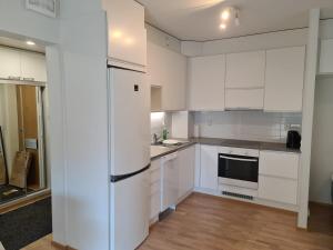 cocina con armarios blancos y nevera en MR Apartments 2, en Vaasa