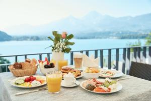- une table avec des assiettes de petit-déjeuner sur un balcon dans l'établissement Hotel Karnerhof, à Egg am Faaker See