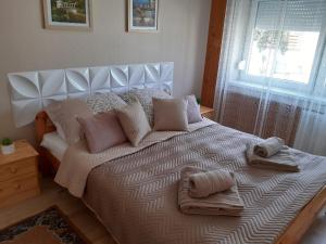 a bedroom with a large bed with pillows and a window at Nyárfa Vendégház in Hajdúszoboszló