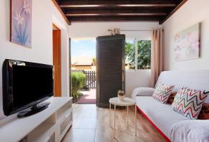 ein Wohnzimmer mit einem TV und einem Sofa in der Unterkunft Casa Yoaki in Corralejo