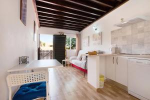 eine Küche und ein Wohnzimmer mit weißen Schränken und einem Tisch in der Unterkunft Casa Yoaki in Corralejo