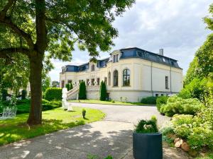 a large white house with a tree and a driveway at Schloss Breitenfeld Hotel & Tagung in Leipzig