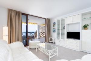 ein Wohnzimmer mit einem weißen Sofa und einem TV in der Unterkunft 120 PLAYA DE LA ARENA Holiday Home by Sunkeyrents in Puerto de Santiago