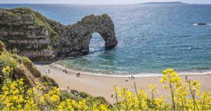 a view of a beach with an arch in the ocean at Nuthatch Cabin at Cloudshill Glade in Wareham