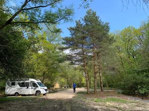 a man walking down a dirt road next to a camper at Nuthatch Cabin at Cloudshill Glade in Wareham
