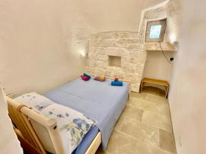 ein kleines Schlafzimmer mit einem Bett in einer Steinmauer in der Unterkunft Trullo Bubamare in San Michele Salentino