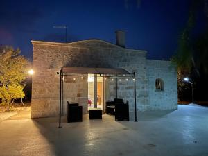 een stenen gebouw met een tent er 's nachts voor bij Trullo Bubamare in San Michele Salentino