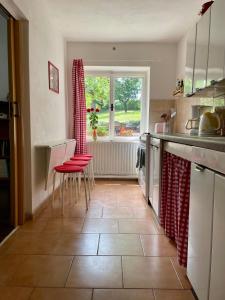 eine Küche mit roten Stühlen, einem Tisch und einem Fenster in der Unterkunft Silver Linden Cottage in Horní Police