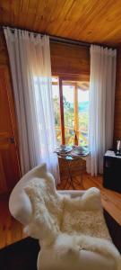 a living room with a couch and a table with windows at Hospedaria Kayser Haus in Urubici