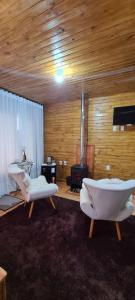 a living room with two chairs and a fireplace at Hospedaria Kayser Haus in Urubici