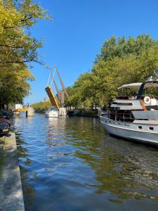 Bed and Breakfast Amsterdam في أمستردام: قارب على نهر مع رافعة في الخلفية