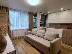a living room with a couch and a kitchen at Apartment near Outlet park by URBAN RENT in Vilnius