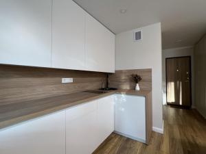 a kitchen with white cabinets and a wooden floor at Apartment near Outlet park by URBAN RENT in Vilnius