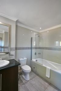 a bathroom with a toilet and a tub and a sink at Regent Kgale Lodge in Gaborone