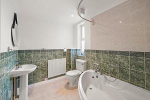 a bathroom with a tub and a toilet and a sink at PRIME 3 BED HOUSE to BICESTER OUTLET for 8 People by Platinum Key Properties in Bicester +21 photos