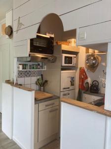 cocina con armarios blancos y nevera blanca en LOCATION LA ROCHELLE, en Saint-Xandre