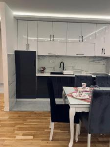 a kitchen with white cabinets and a table and chairs at Apartman LUX in Bijeljina