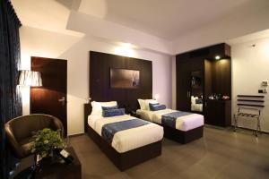 una habitación de hotel con 2 camas y una silla en Best Western Elyon Colombo, en Colombo