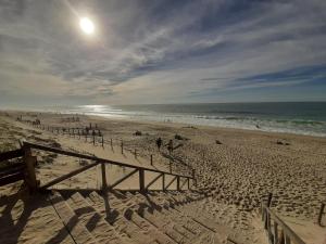 a beach with people walking on the sand and the ocean at Maison 4 personnes tout confort à 300m de la plage - Clim & Wifi in Mimizan-Plage